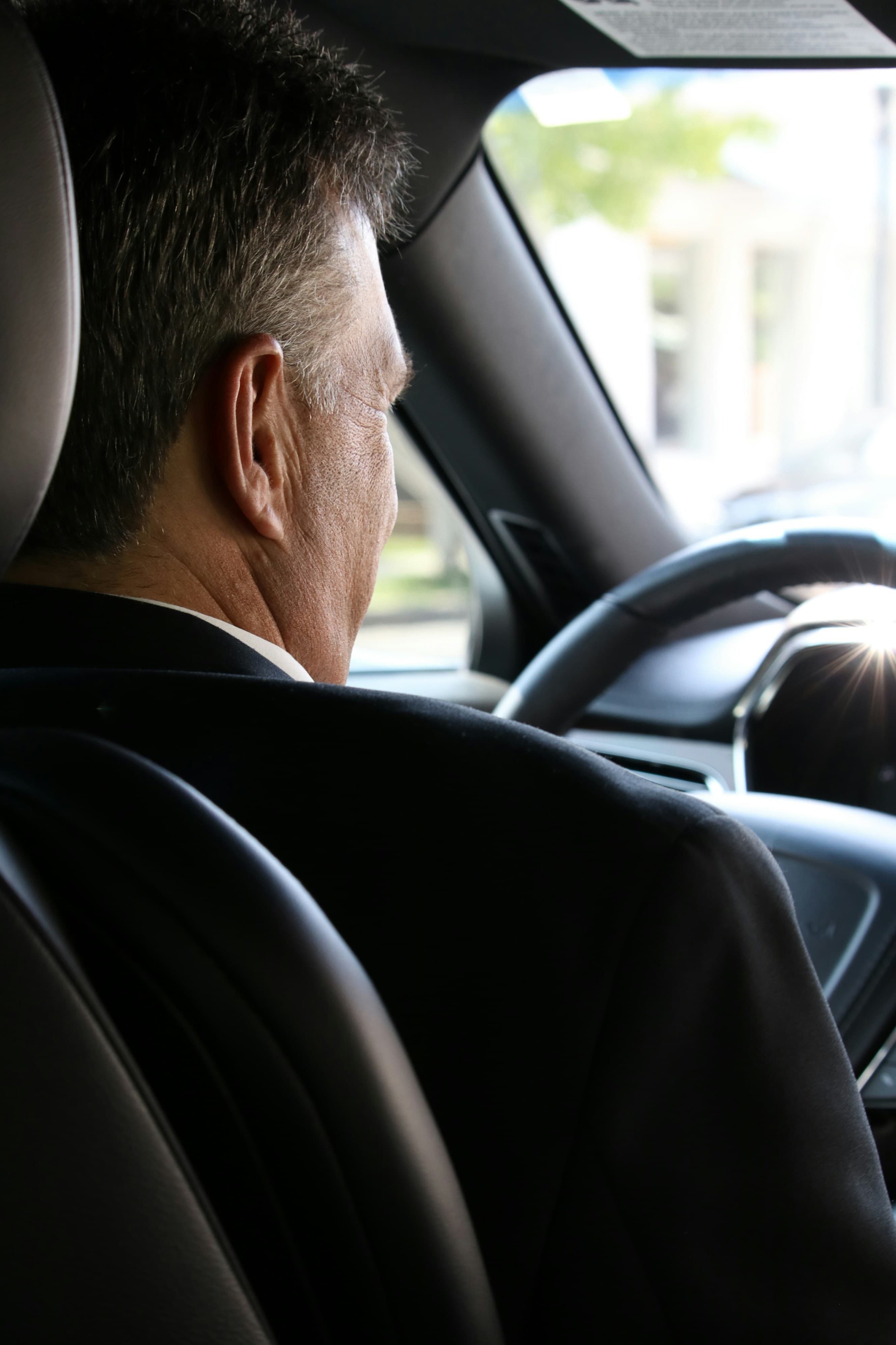 Chauffeur in formal black attire driving an executive vehicle